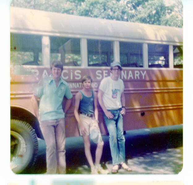 Three teenage boys beside vintage yellow school bus